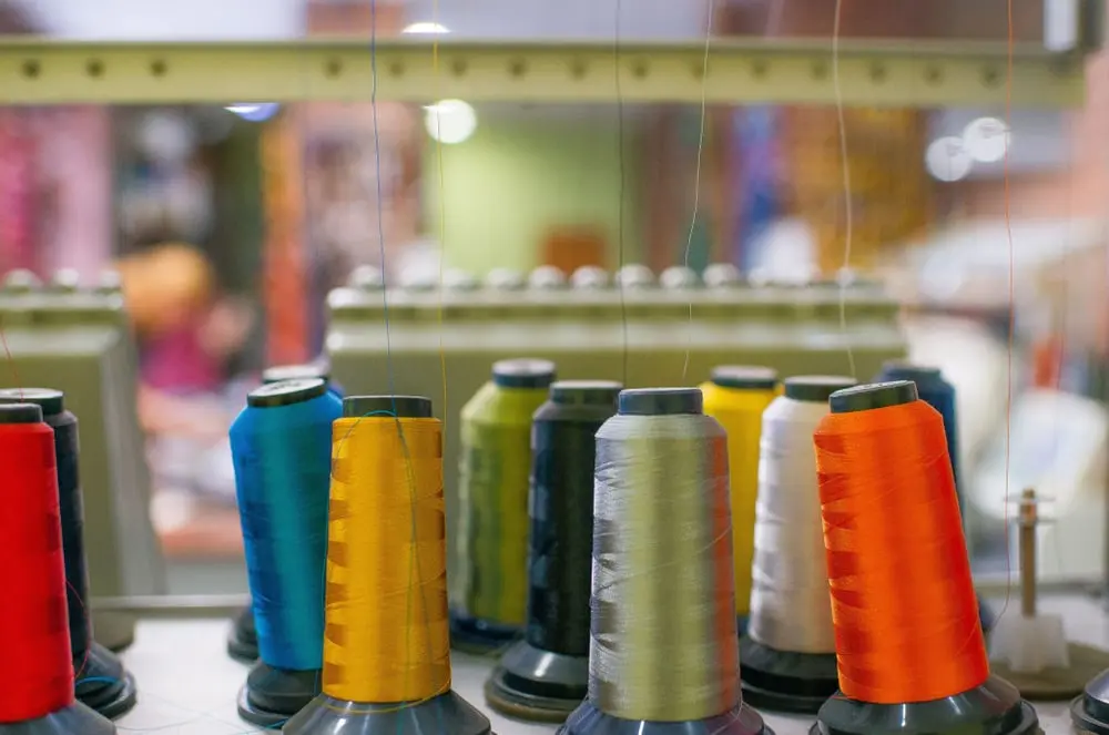 Bobines de fil colorées dans un atelier de couture, illustrant les marges des fabricants britanniques