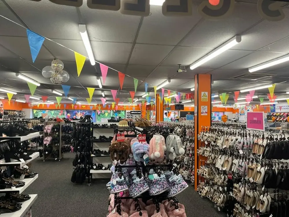 Magasin de chaussures Wynsors avec rayons pleins et décorations festives colorées en vue de l'acquisition par Modella