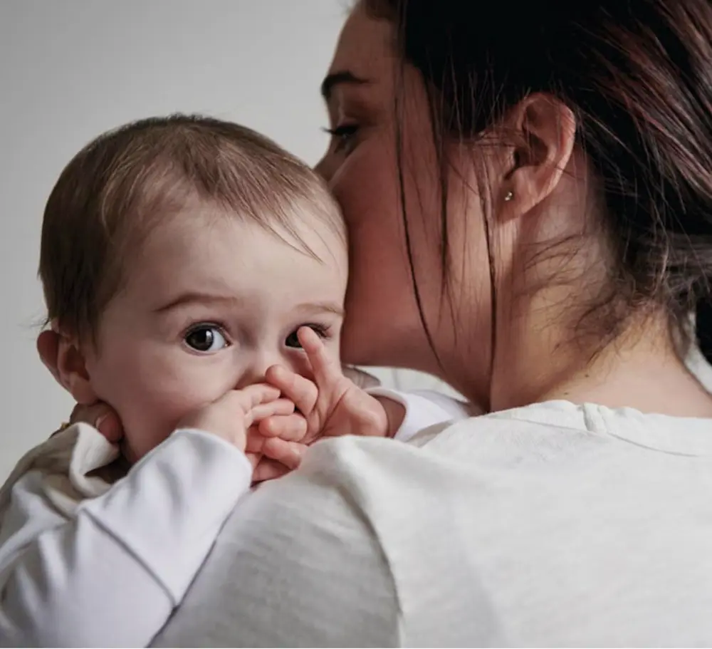 Une mère tient un bébé dans ses bras, évoquant la tendresse liée à Mothercare