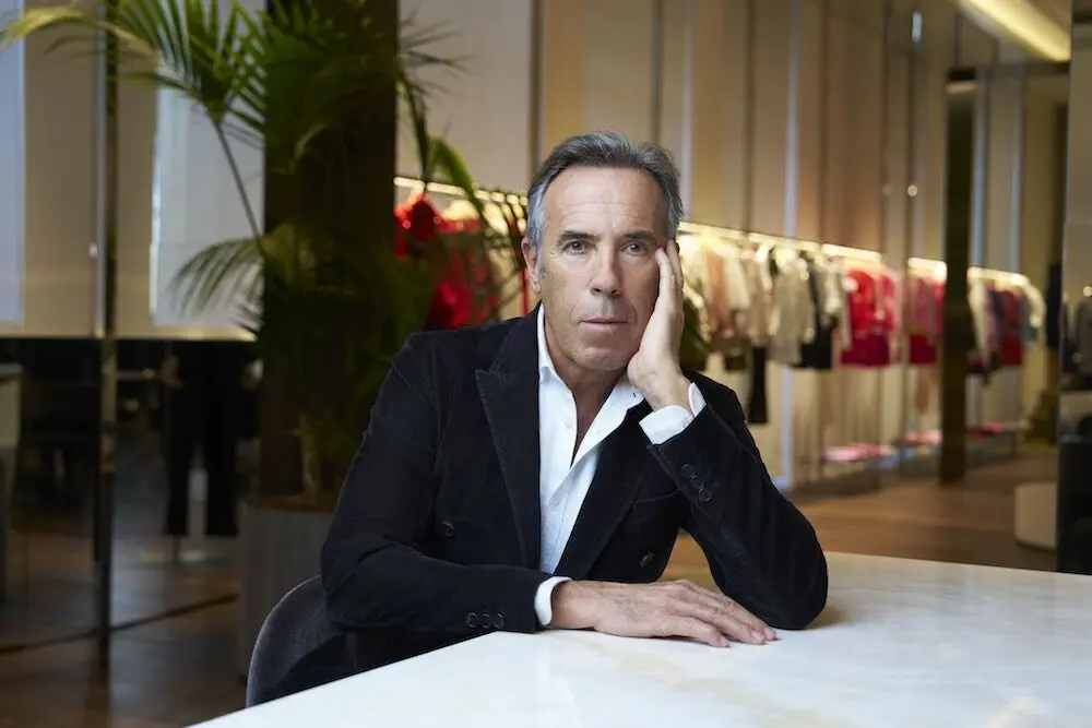 Un homme assis dans un espace moderne avec des vêtements en arrière-plan, évoquant la marque OVS