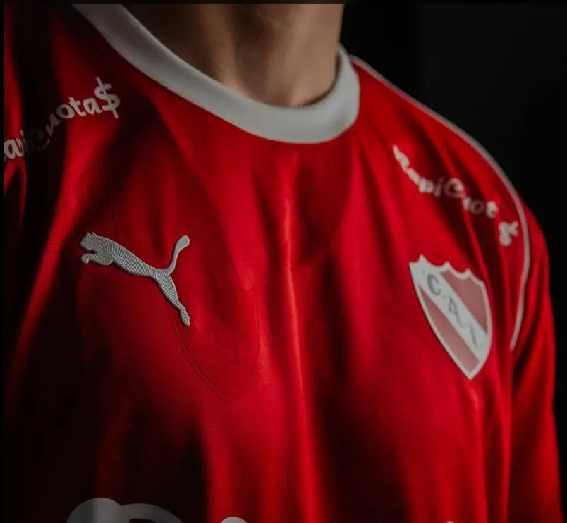 Maillot rouge avec logo Puma et écusson de club de football sur fond sombre, symbole de la marque en difficulté