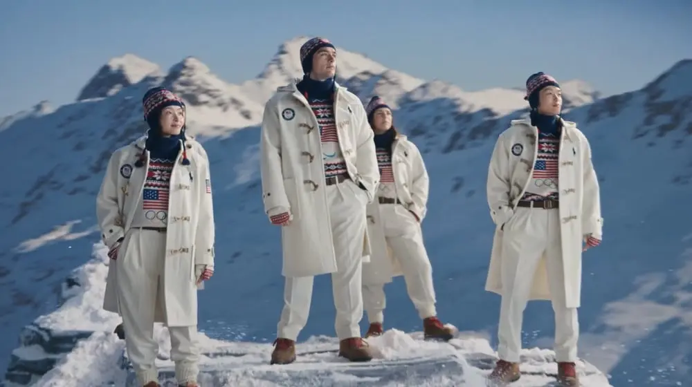 Des athlètes de Team USA en tenues Ralph Lauren posent sur un sommet enneigé avec des montagnes en arrière-plan