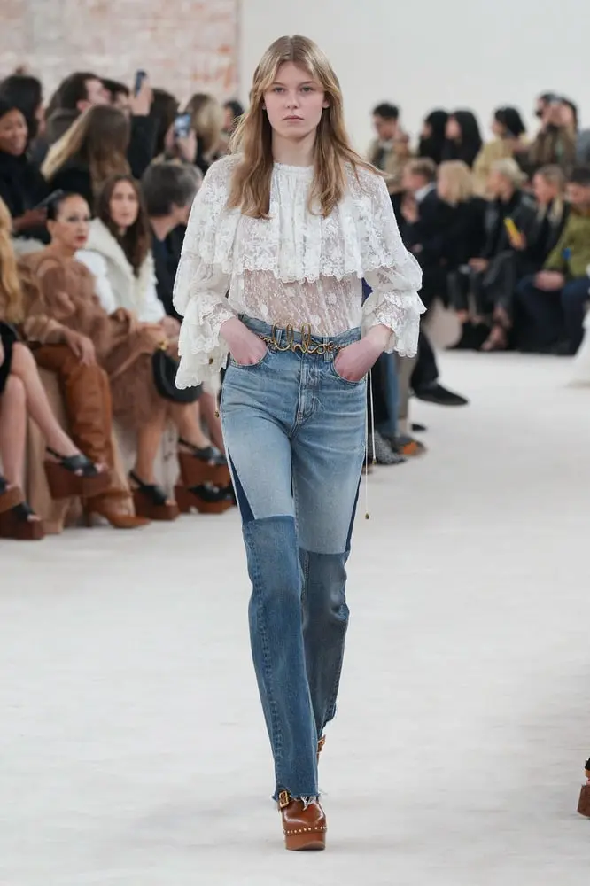Défilé de mode avec mannequin en haut blanc dentelle et jean, en lien avec la hausse de Richemont UK