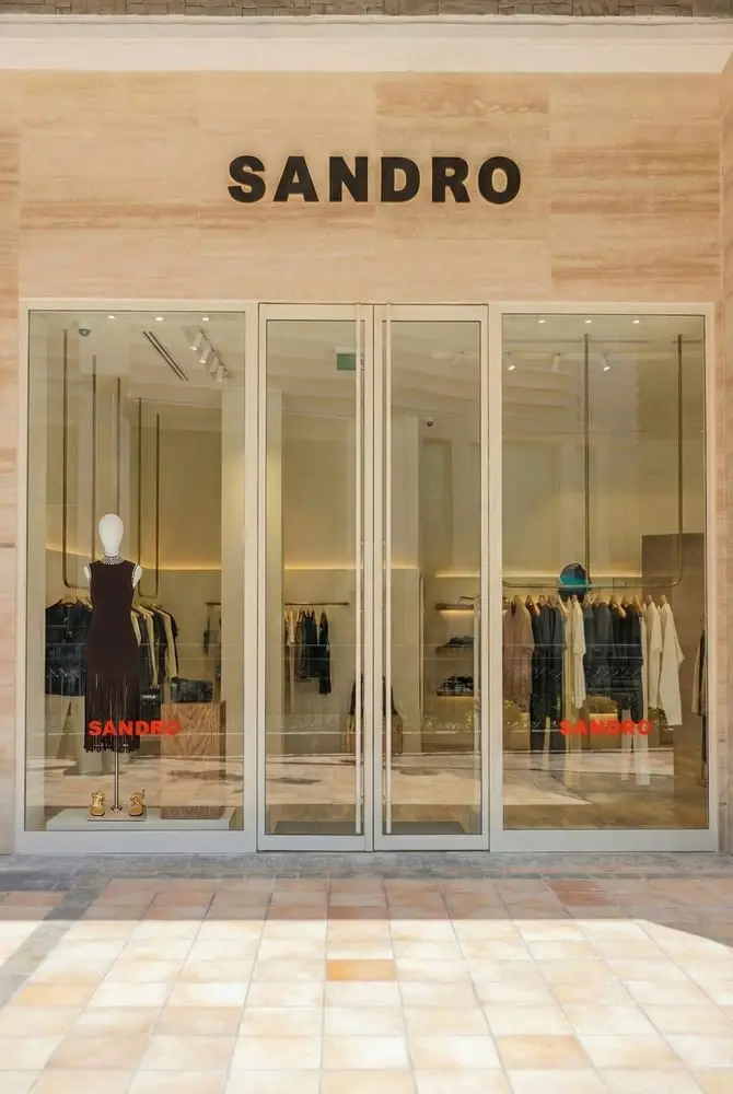 Façade de la boutique Sandro avec vitrine exposant une robe et des vêtements accrochés à l'intérieur.