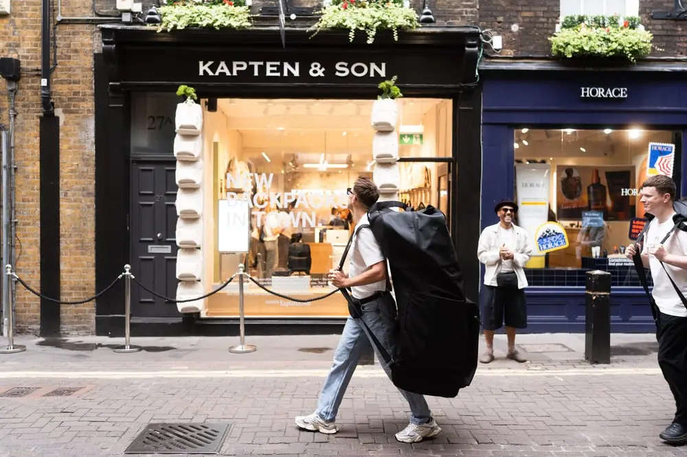 Des piétons portant de grands sacs à dos passent devant la boutique Kapten & Son à Londres.