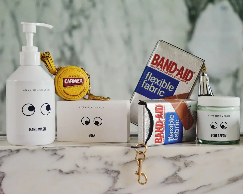 Produits Anya Hindmarch x Boots sur fond marbré, incluant un savon, un soin des pieds et des pansements Band-Aid