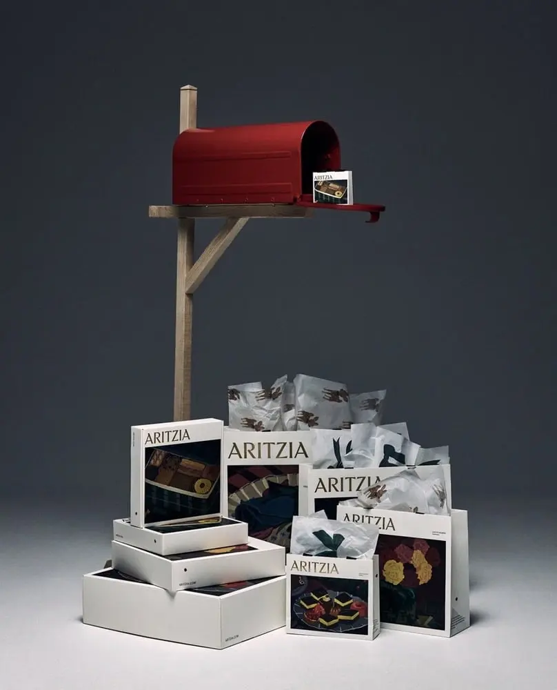 Boîte aux lettres rouge avec sacs et boîtes de vêtements Aritzia, symbolisant le succès financier de la marque