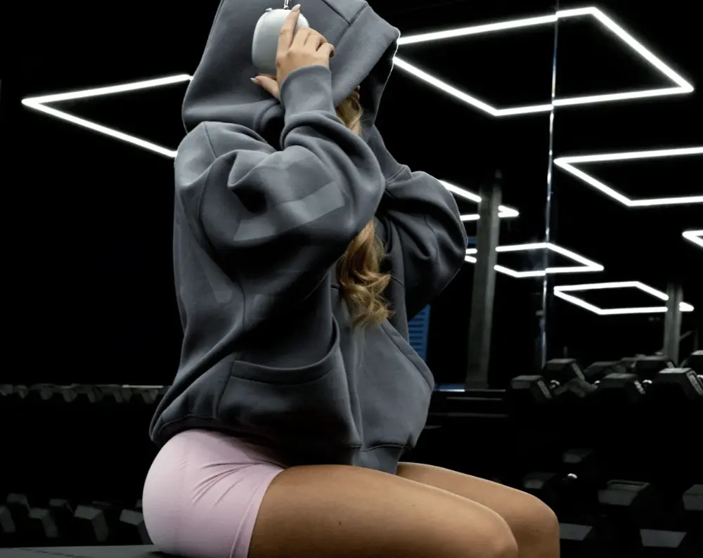 Une personne en vêtements de sport assise dans une salle de sport moderne, illustrant l'image de marque Dfyne.