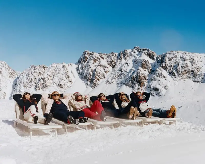 Des athlètes en vêtements J.Crew se détendent sur des chaises longues dans la neige, montagnes en arrière-plan