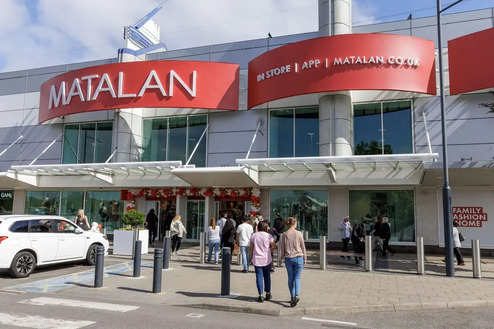 Des clients entrent dans un grand magasin Matalan sous un ciel légèrement nuageux.