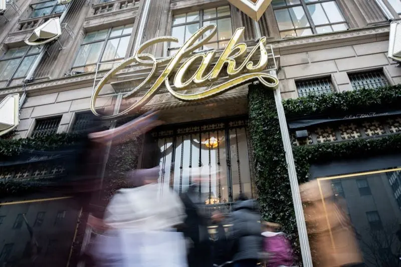 Façade du magasin Saks avec passage flou de piétons devant l'entrée principale ornée du logo Saks.