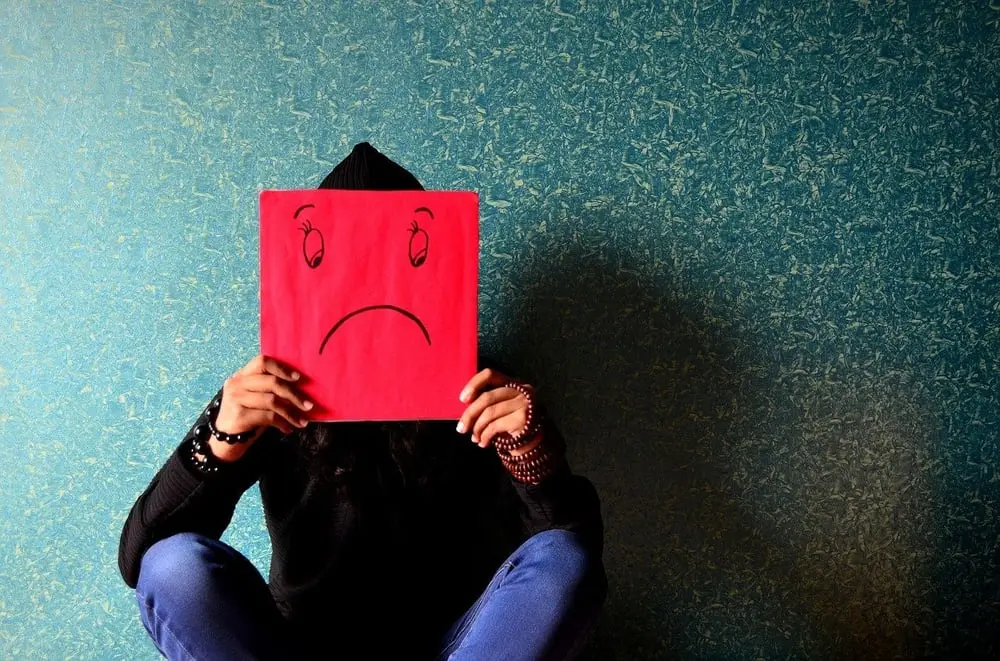 Une personne assise tient un dessin de visage triste, symbolisant la détresse du secteur retail en Europe