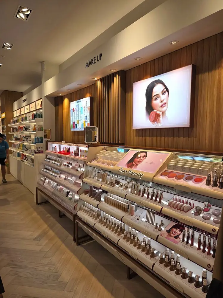 Espace de vente Space NK présentant des produits de beauté Rare Beauty illuminés par des étagères bien remplies