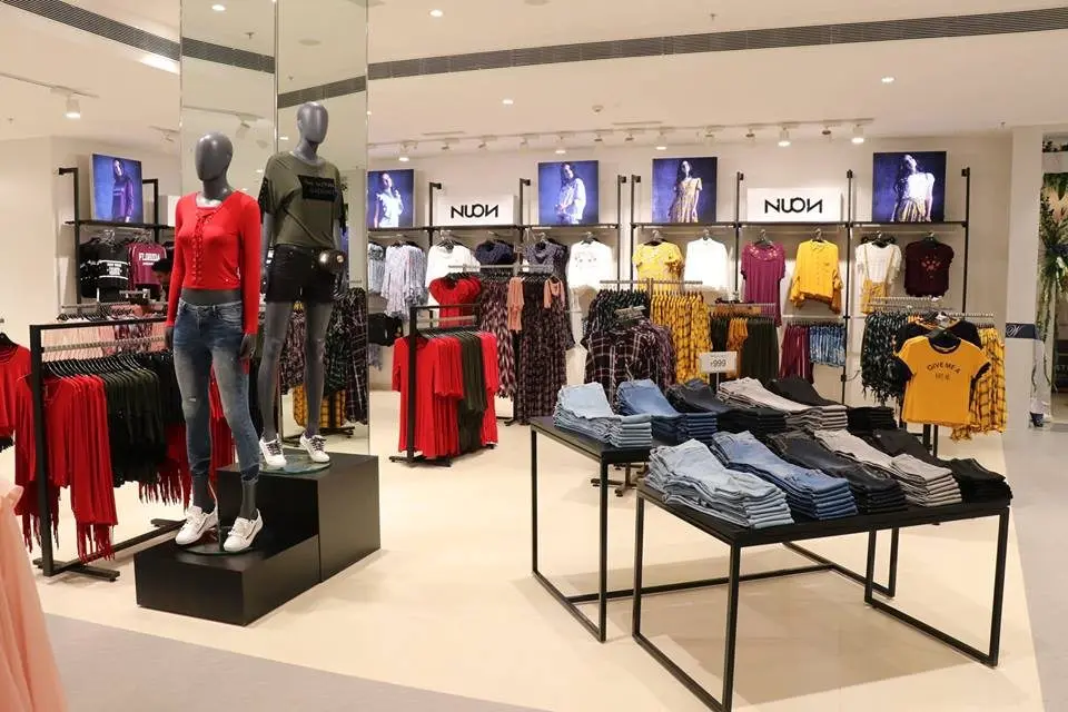Magasin Trent Ltd avec mannequins habillés et vêtements colorés sur étagères et tables d'exposition
