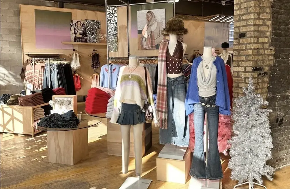Magasin Urban Outfitters avec mannequins portant des tenues d'hiver parmi des vêtements colorés et un arbre de Noël scintillant