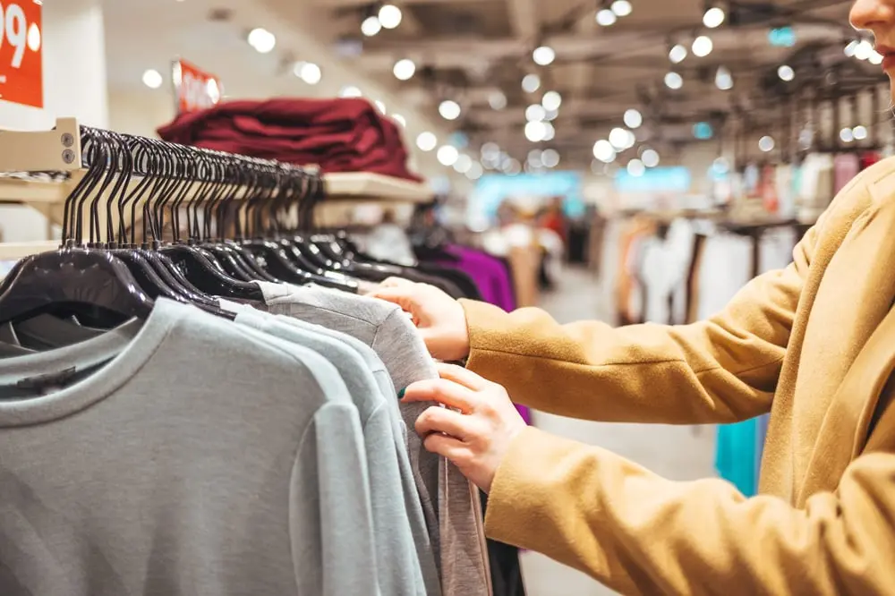 Personne choisissant des vêtements dans un magasin, illustrant les ventes de textiles en France