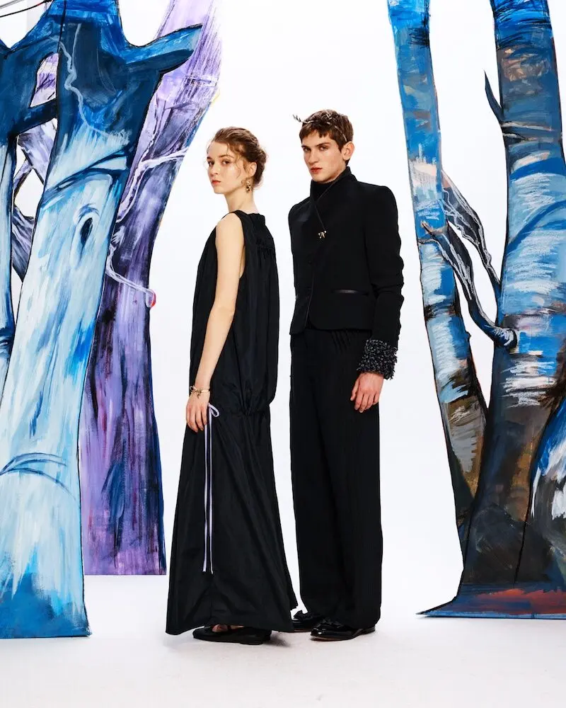 Deux mannequins posent en vêtements noirs devant des décors artistiques colorés pour la mode homme Vivetta.